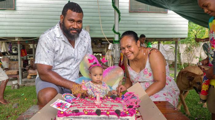 Parents with their daughter at a first birthday cake