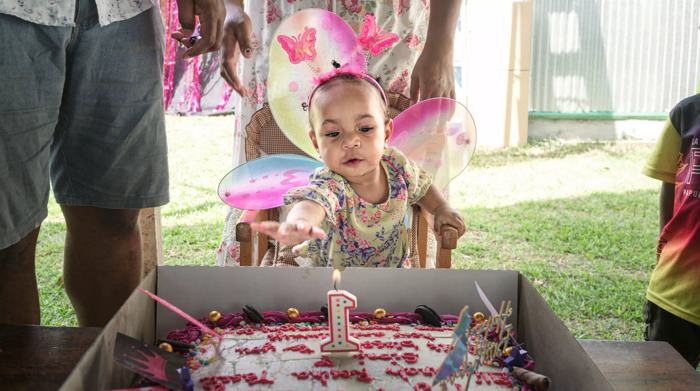 Toddler in fairy wings at her birthday cake
