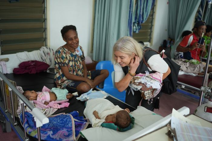 Visitor with mothers and babies in a hospital ward