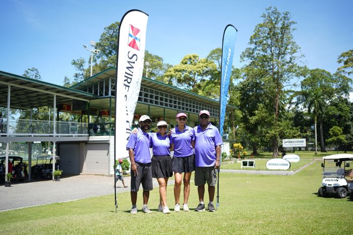 Corporate golf team beside sponsor banners