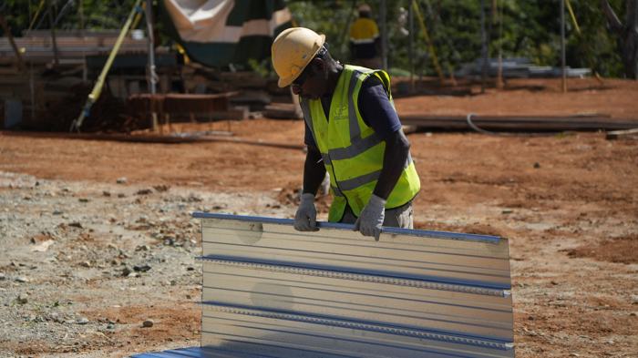 Worker handling roofing sheets on site